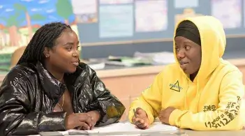 two individuals at a desk talking