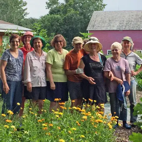 a group of gardeners standing outside next to a grove of flowers