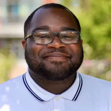 Photo of Mister smiling outside the Davis Center on a sunny spring day