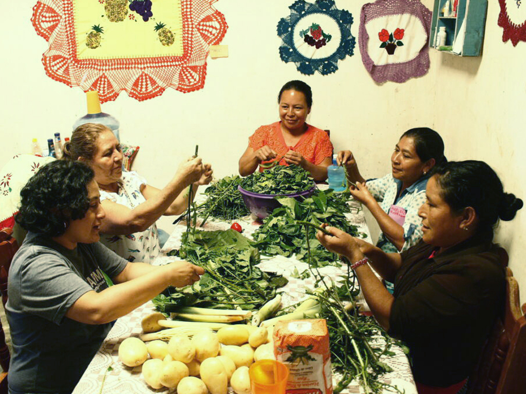 People sitting at a table preparing vegetables