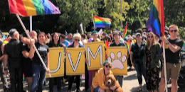 Students, staff and faculty posing with rainbow flags and sign that says UVM at Burlington Pride Parade