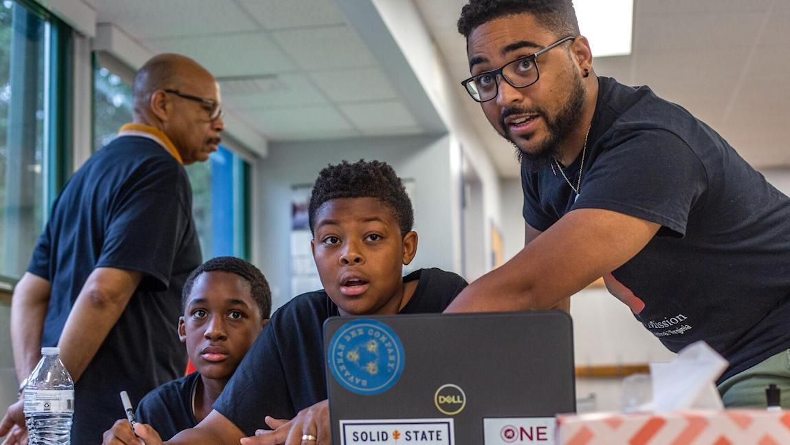 Daniel Farley works with young black males in a school classroom.