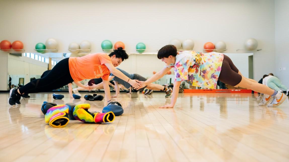 Two students hold a plank pose in group fitness glass