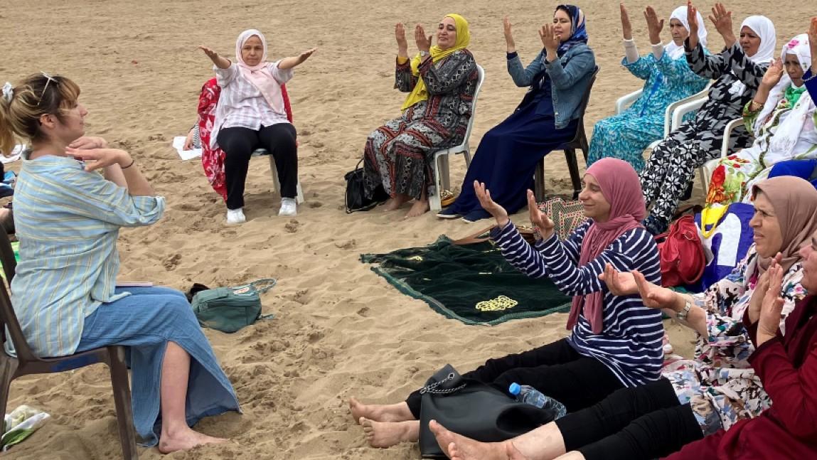 On a beach in Morocco, a UVM occupational therapy student leads a chair yoga session with women undergoing treatment for cancer.