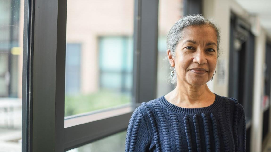 Beverly Belisle standing and smiling in front of a window in Living and Learning