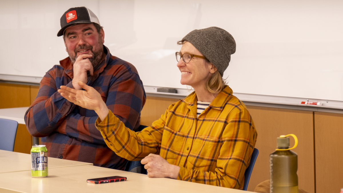 Hilary Martin smiles and extends hand. Ransom Conant smiles at her. They sit at a panel.