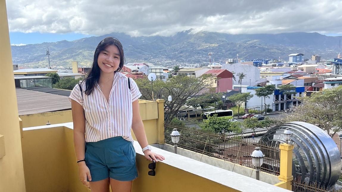 Juliana posing on the roof of a building overlooking the city and mountains.