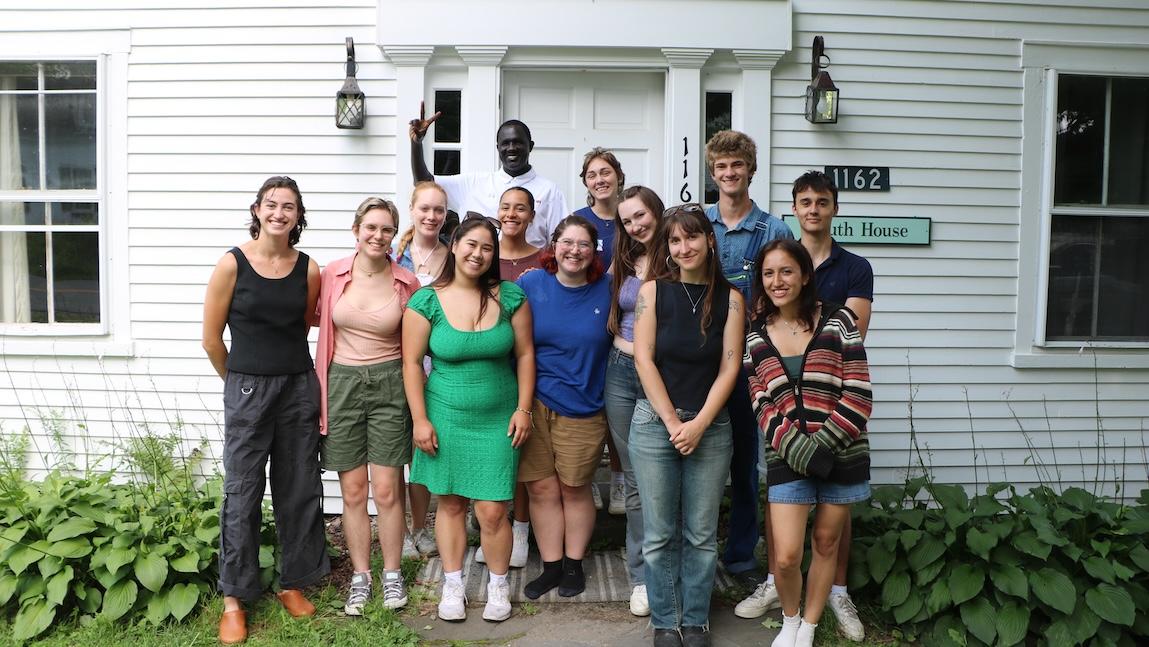 Group of UVM students standing in front of a white house