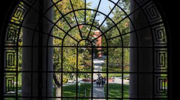Looking out from a multi-paneled window to the university green.
