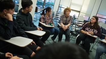 five students at desks talking