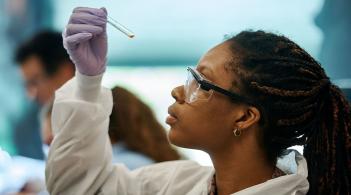 a person holds a vial in the air while inspecting it