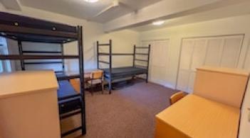 A bedroom with a double bunk and a single bed, closets, desks, and dressers.