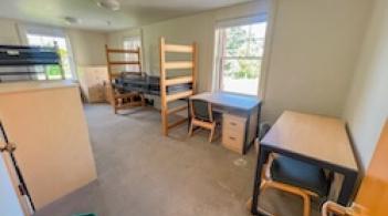 A room with three beds, three dressers/closets, and three desks.