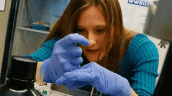 a gloved student performing an experiment in a chemistry lab