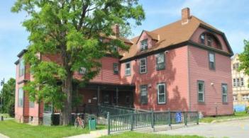 External shot of the Allen House. It is a red building with a brown roof and green trim around the windows.