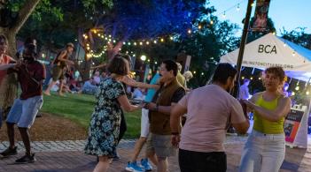 People of different races wearing summery clothing salsa dancing in downtown Burlington in the early evening