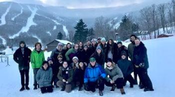 A group of students at a ski resort in the winter posting for a photo