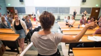 a person standing at the top of a lecture hall directing students where to sit