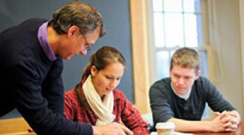 A group of students and teacher working on papers in a classroom