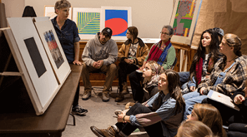 Professor with students discussing art pieces