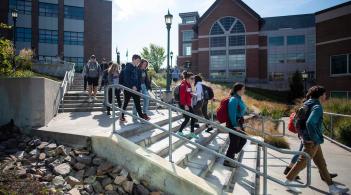 A group of students walk down stairs on their way to class.