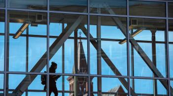 A student walks across a sky bridge between academic buildings.