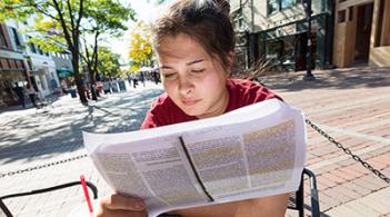 A student sitting outside while reading