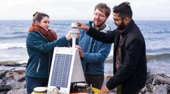 Three researchers examining a climate buoy.