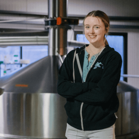 Kristen poses near brewery equipment
