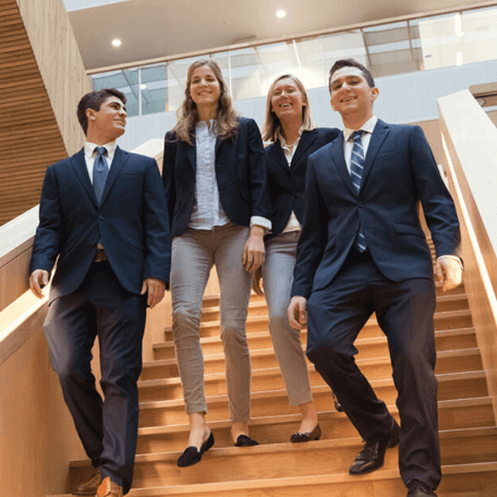 Students wearing business attire descend the stairs