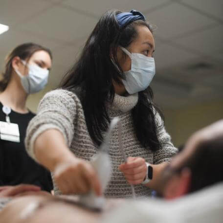 two students practice ultrasound on volunteer patient