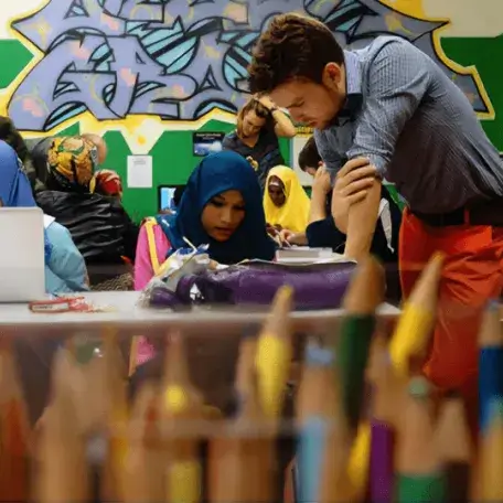 Instructor assisting students in a colorful community learning space.