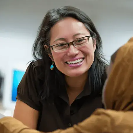 Mentor smiling and talking with a student at a computer lab.