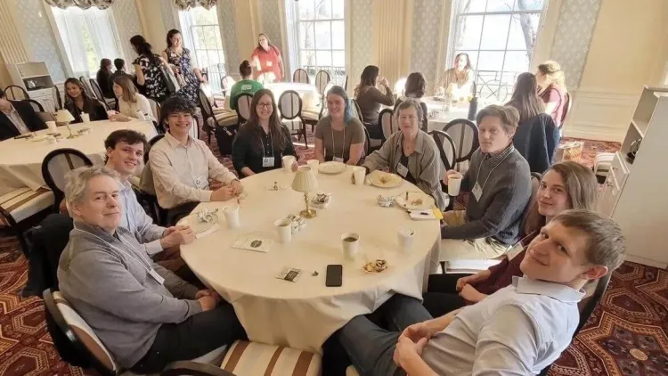 Pierre sitting at a circular table along with his peers and professors at the New York Chapter of the American Fisheries Society 2024 Annual Meeting