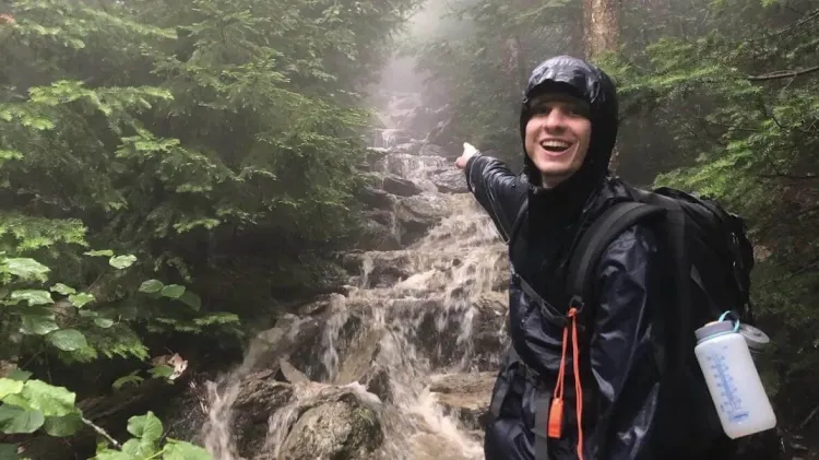 Pierre smiling and pointing at a waterfall.