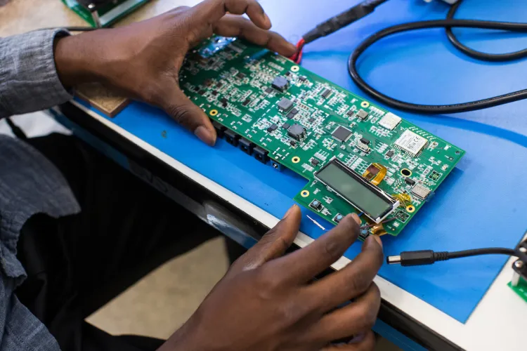 A student's hands inspects a circuit board