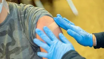 Nurse placing bandaid over vaccine injection site