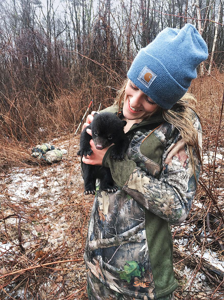 caitlin drasher holds a baby black bear