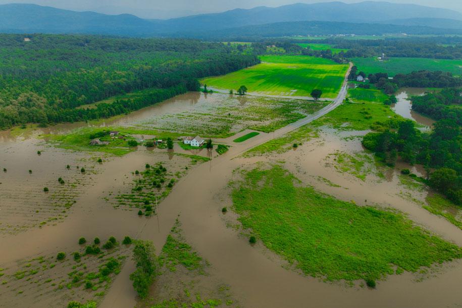 a farmhouse sits in the middle of flooded fields in Middlebury
