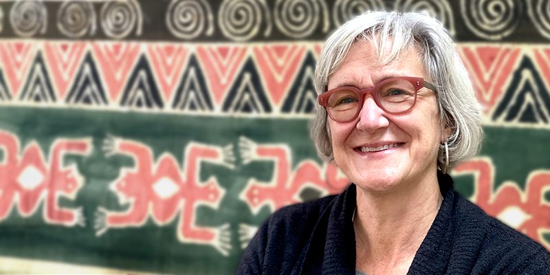 Polly ericksen smiling at the camera in front of a green and red pattern