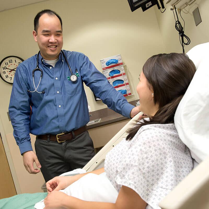 a nurse smiles at a patient in a hospital bed