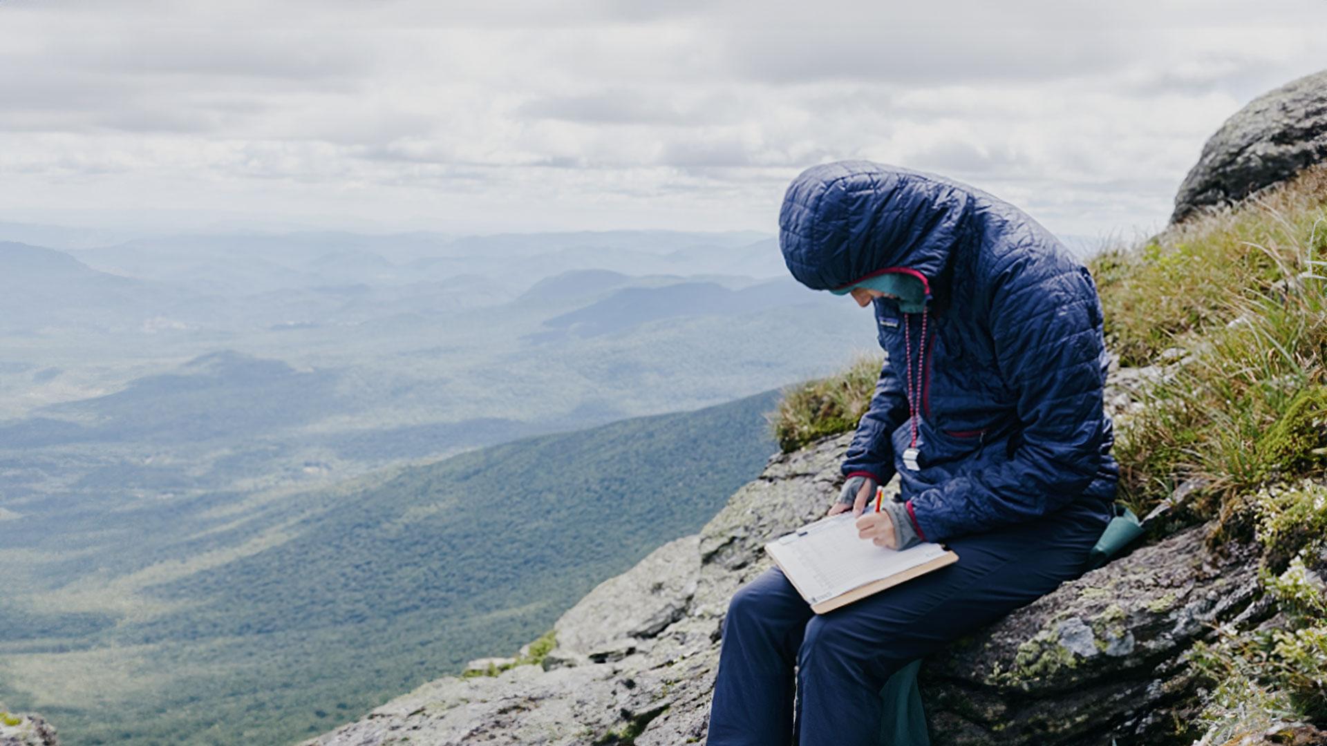 a person in a puffy jacket studies on top of a mountain