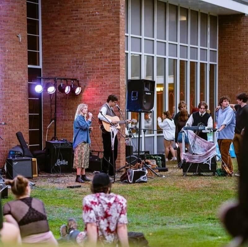 Student perform and gather on an outdoor stage.