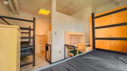 A residence hall room with two beds, two desks, two dressers, two wardrobes, and a wall divider.