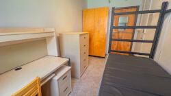 Residence hall room with one bed, one desk. one dresser, and one wardrobe.