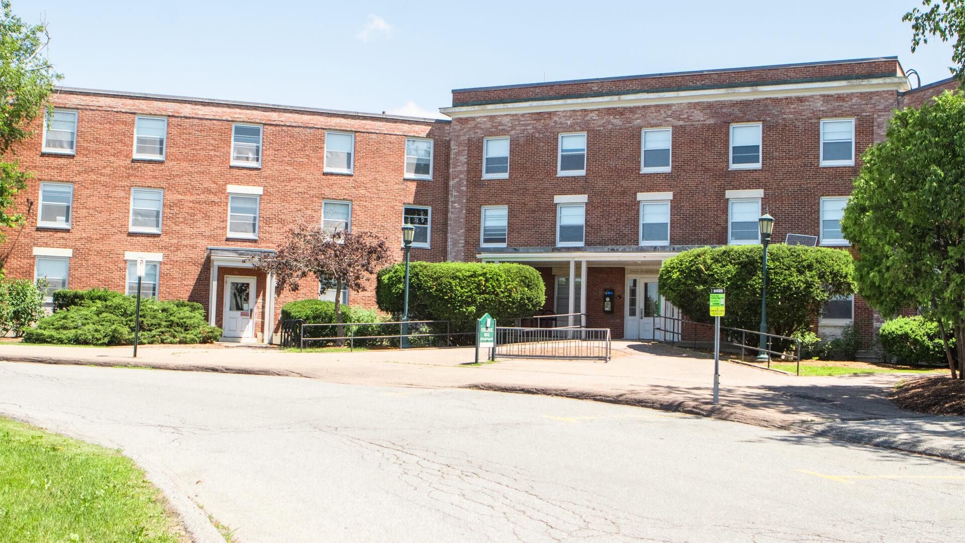 Ground view of curved brick three-story residence hall. 