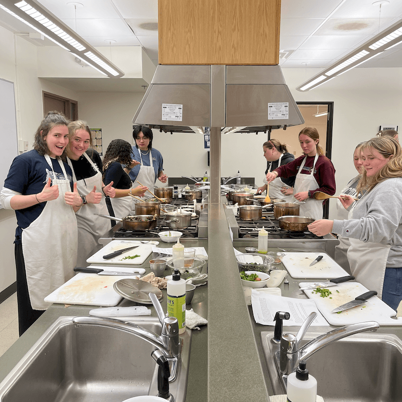 A group of students in a large kitchen cooking.