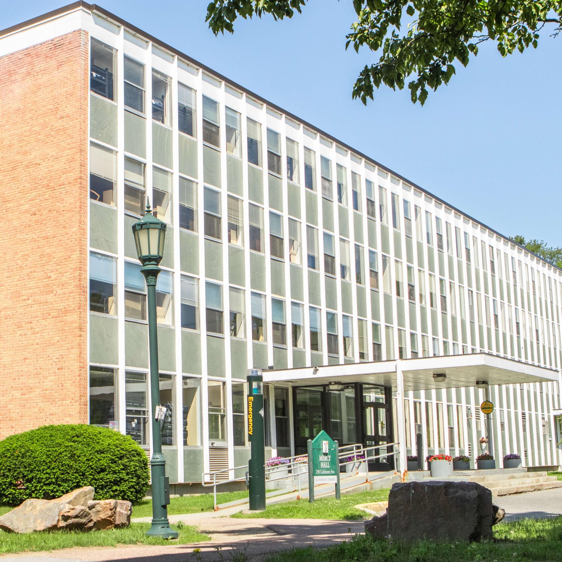 A four-story brick residence hall with a wall of windows. 