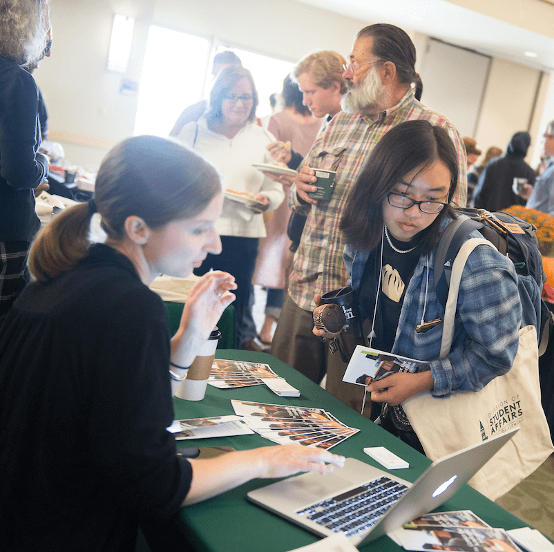 A student talks with a counselor at an event table
