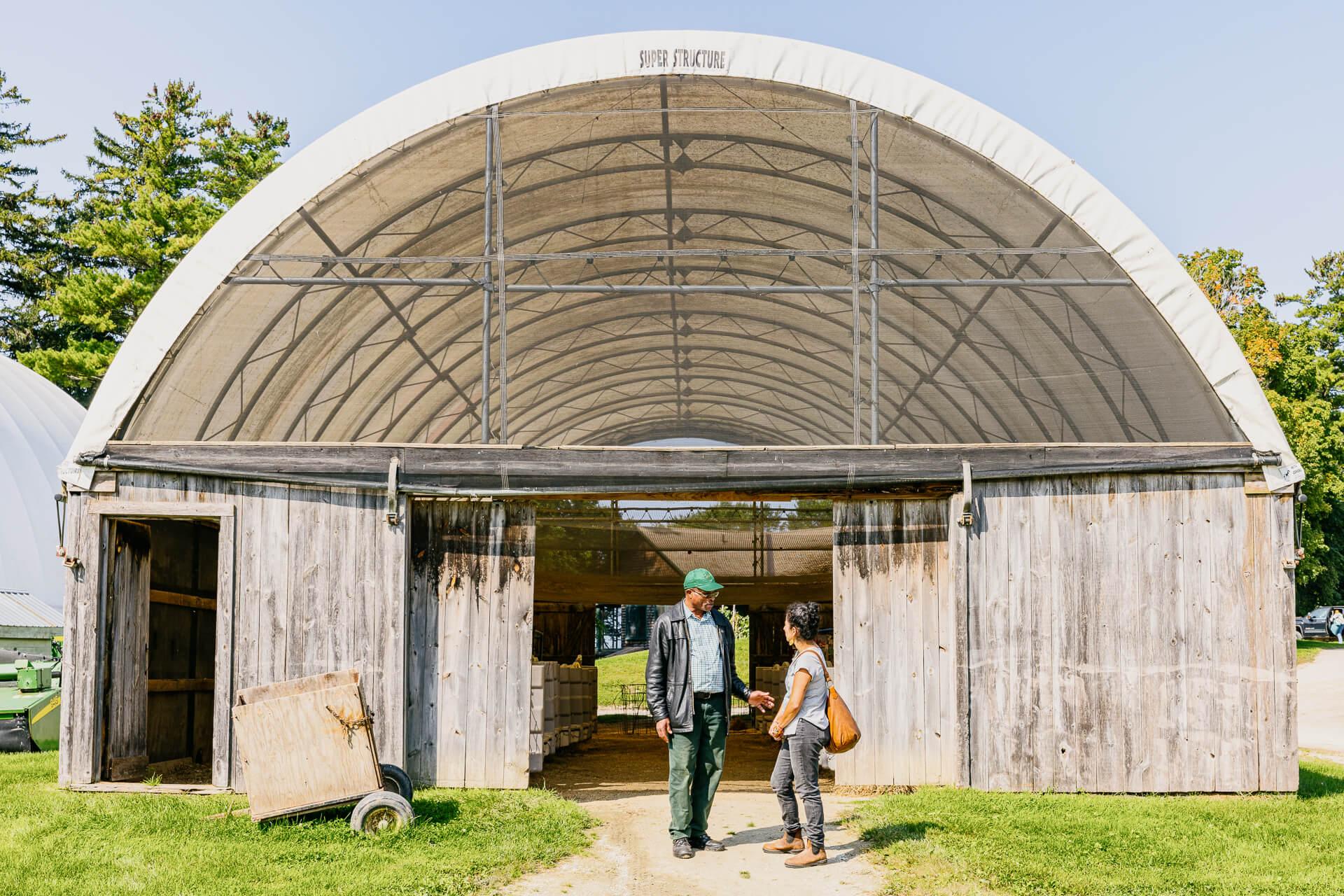 Two people standing in front of a barn building